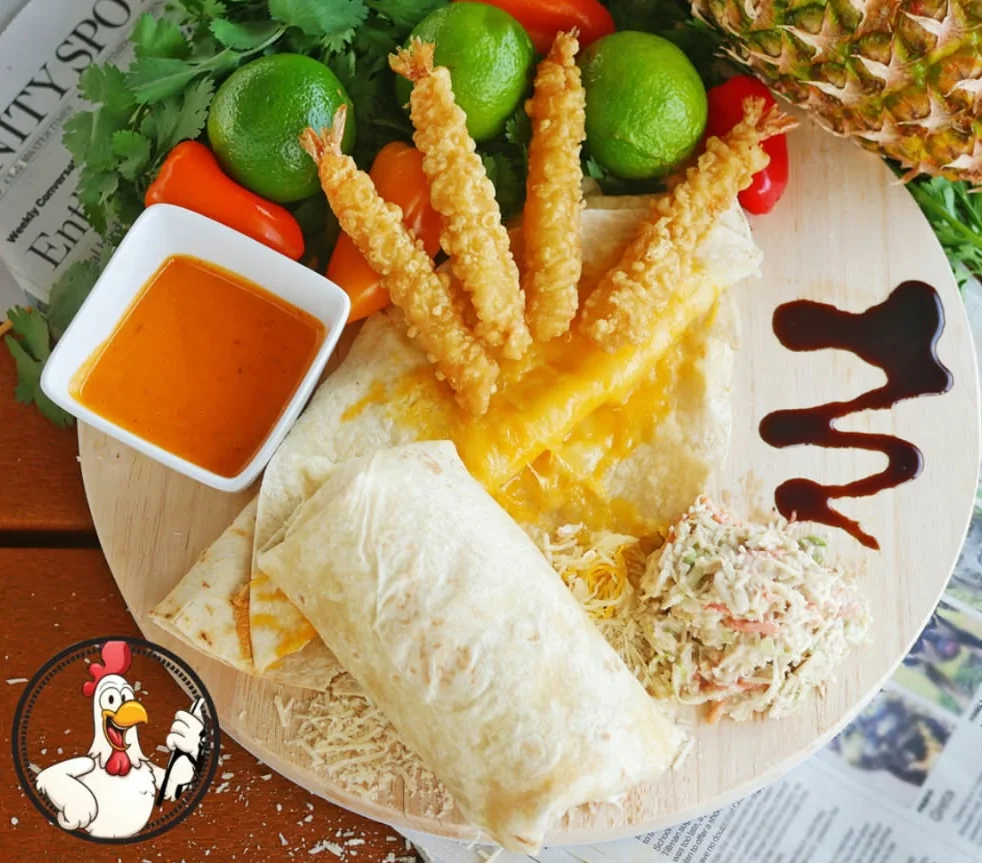 Boom Boom Shrimp Wrap on a wooden board with tempura shrimp, slaw and a cup of sauce