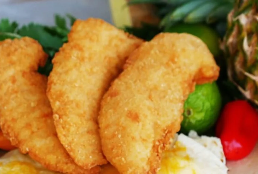 Three golden battered chicken tenders with limes and peppers